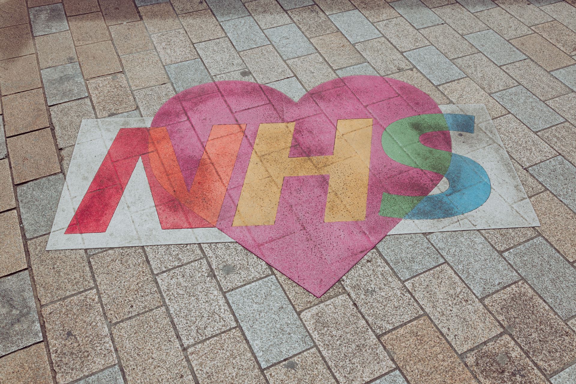 The NHS logo over an image of a heart, printed on a pavement