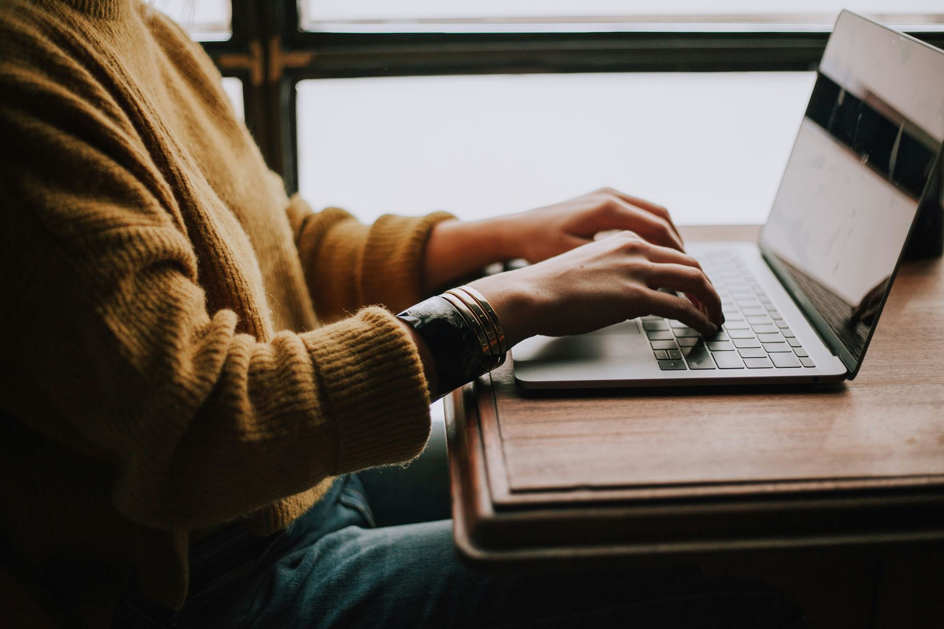 A person sitting at a desk and using a laptop