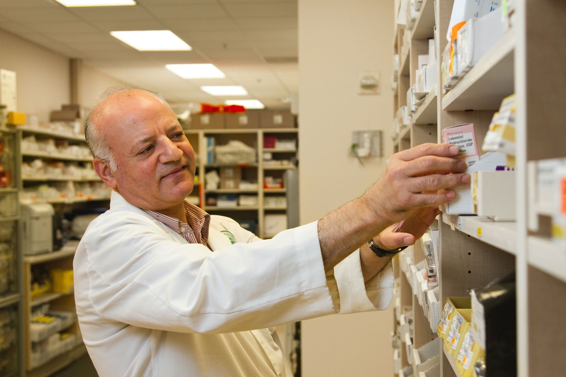 a man working in a pharmacy looking at medication
