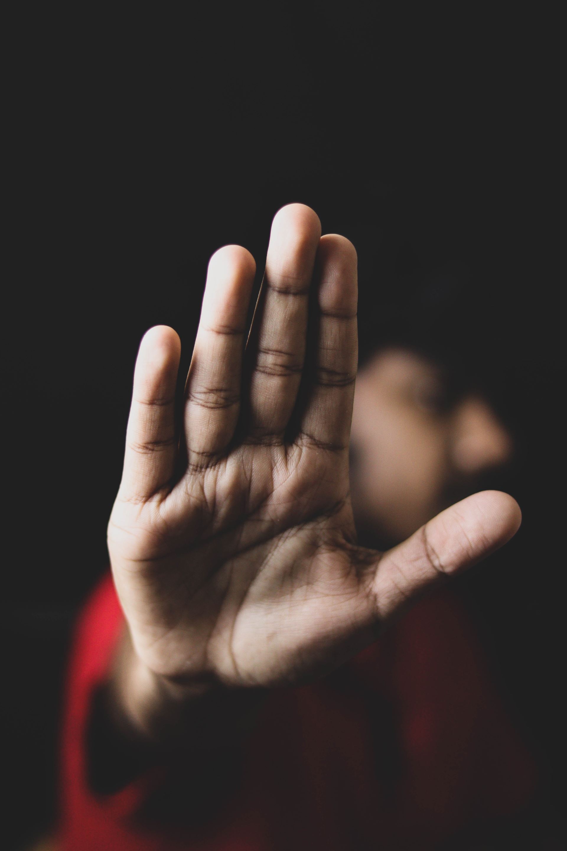 A person holding their hand up and turning their head away behind.