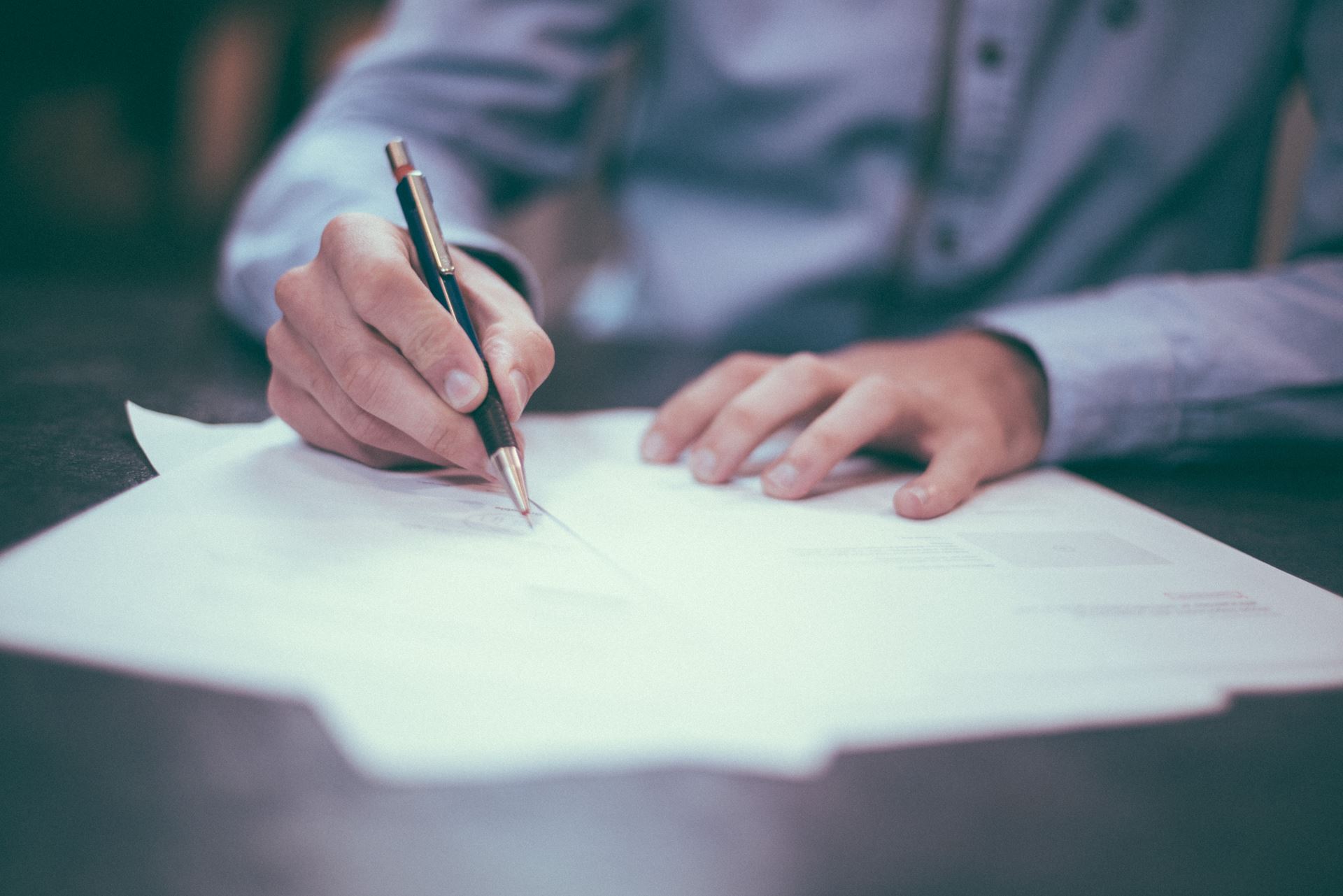 A person filling in a form with a biro pen