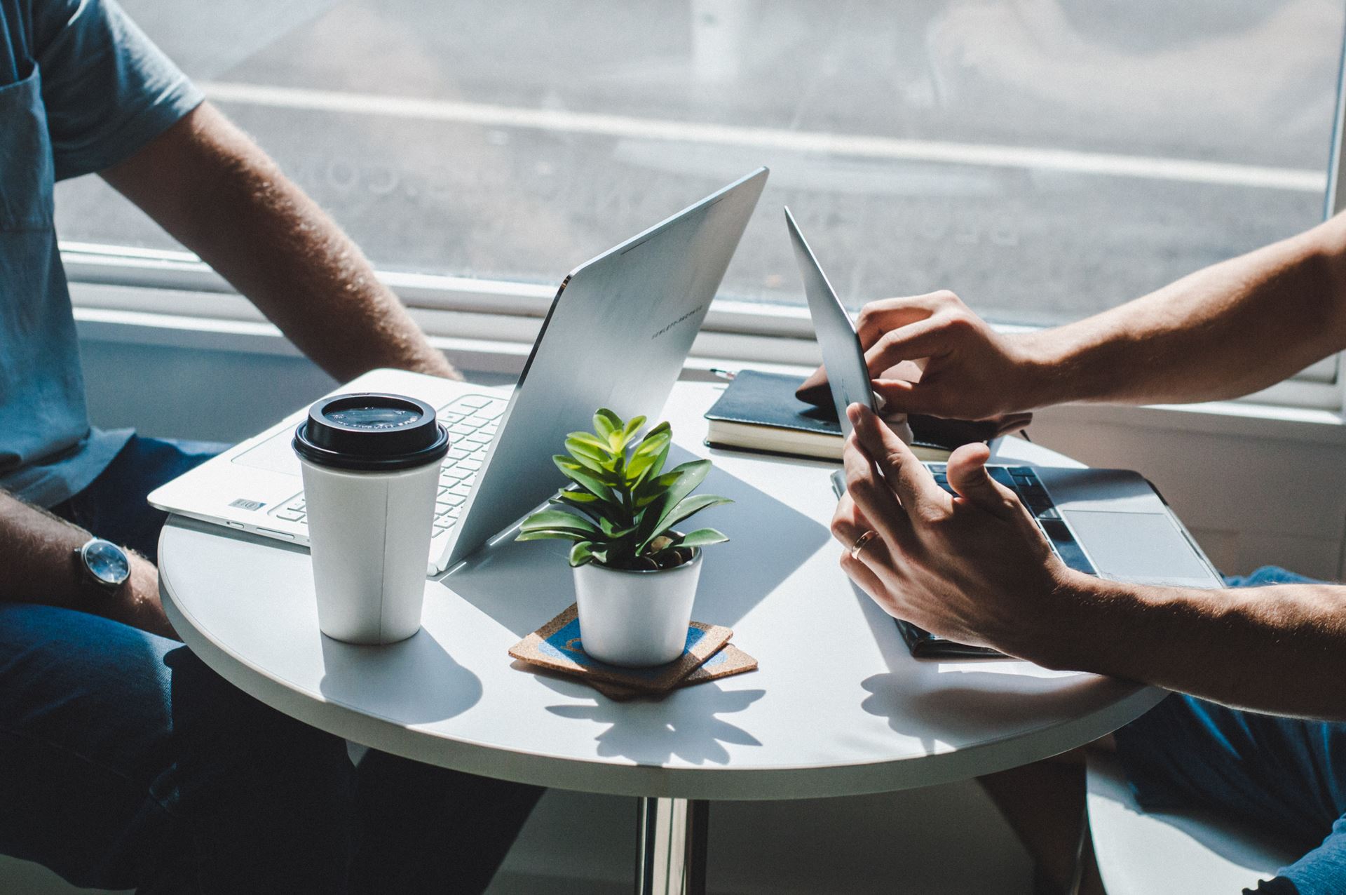 Two people sitting opposite each other at a table whilst using laptops 