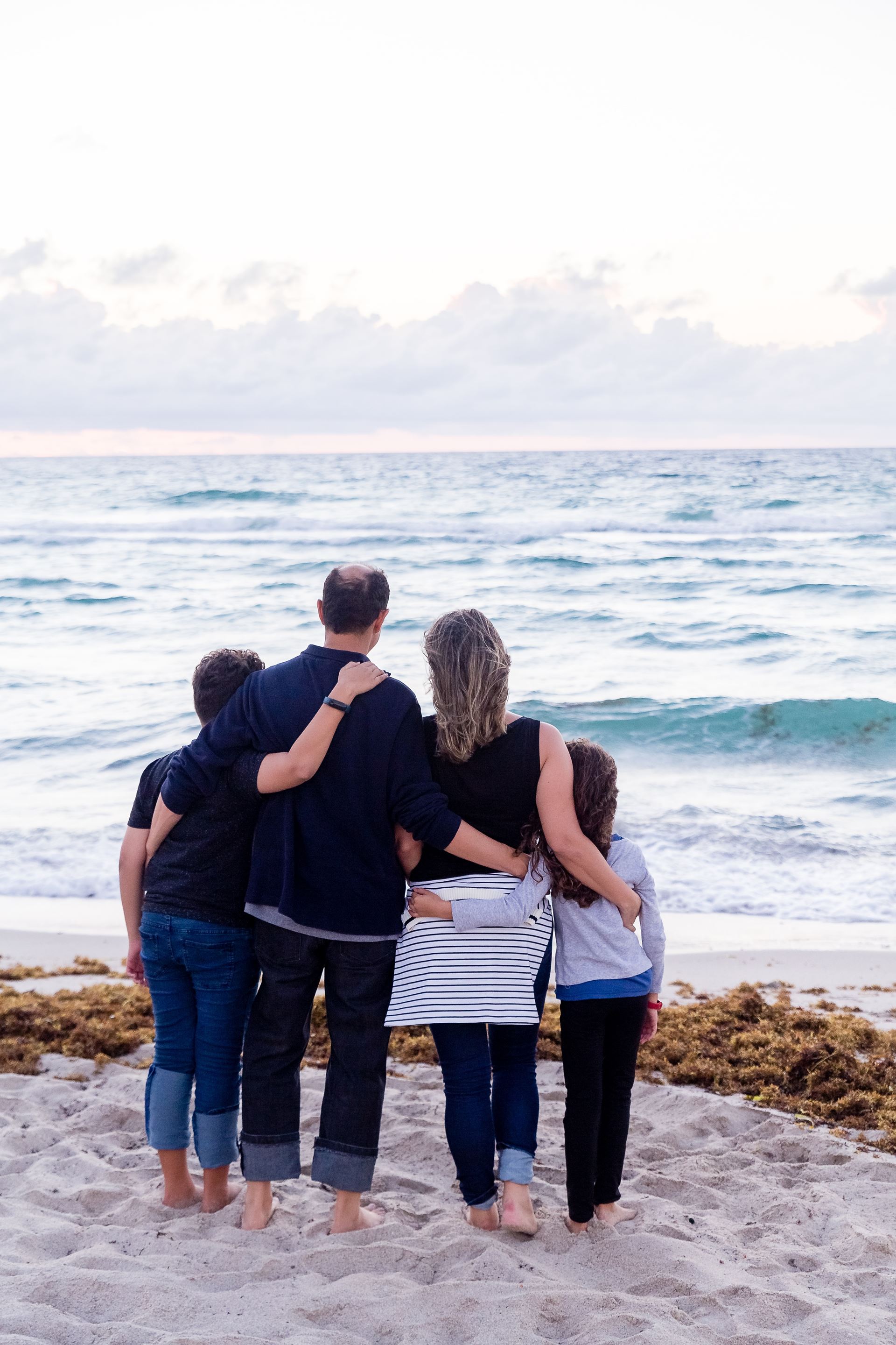 A family of two parents and two children on a beach looking at the sea